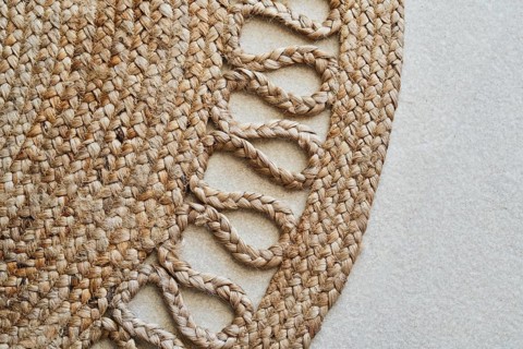 Detailed close-up of a braided jute rug showcasing its intricate woven design. The natural fibers