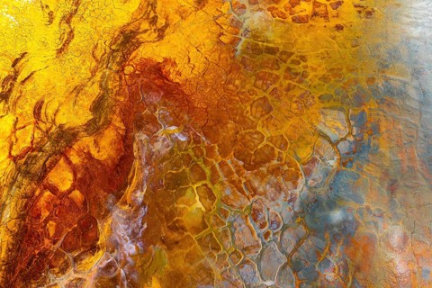 A vivid image showcasing a multicolor mud surface with intricate textures and abstract patterns The
