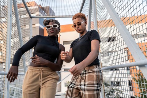 A vibrant LGBT multiethnic couple poses joyfully in a modern urban setting, exuding confidence and