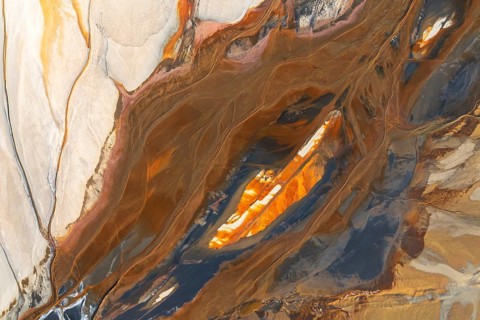 Abstract texture featuring swirling earthy tones intermixed with vibrant orange, cream, and teal