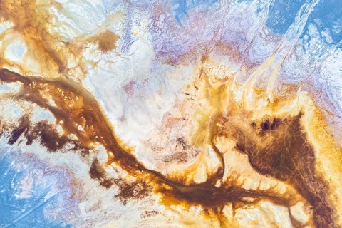 A vibrant abstract texture blending earthy browns and celestial blues, evoking landscapes and