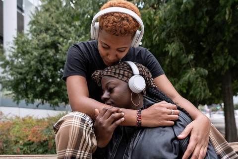 An affectionate multiethnic LGBT couple, embracing outdoors, share a tender moment while both
