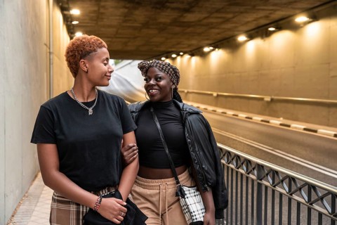 An LGBT multiethnic couple shares a joyful moment while strolling through an illuminated urban