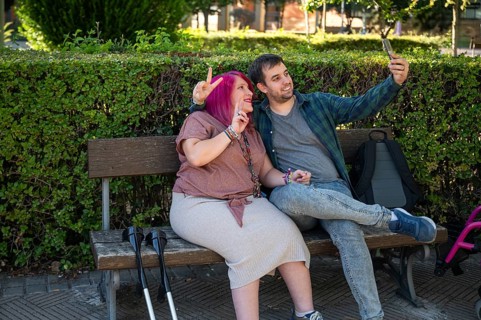 A college couple sitting on a bench, capturing a joyful moment together The woman uses crutches,