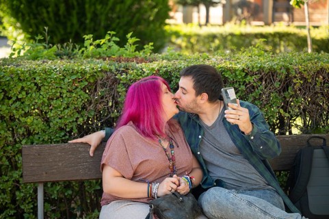 A college couple shares a tender kiss on a campus bench The woman, embracing life with a disability