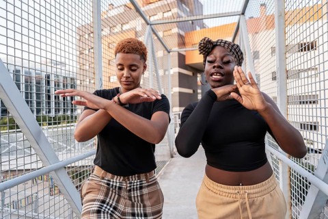 A lively LGBT multiethnic couple dances energetically on an urban bridge, expressing joy and