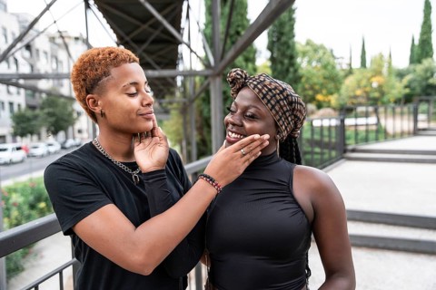 A joyful LGBT multiethnic couple shares a tender moment outdoors, gently touching each other's