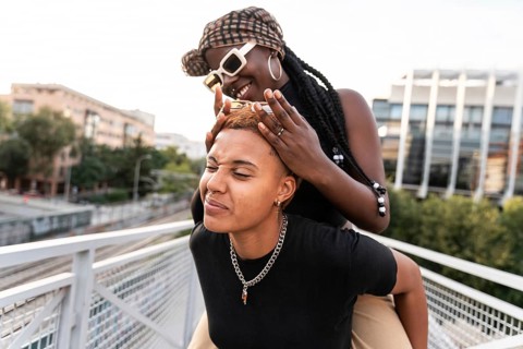 A joyful LGBT multiethnic couple shares playful moments outside. They enjoy each other's presence