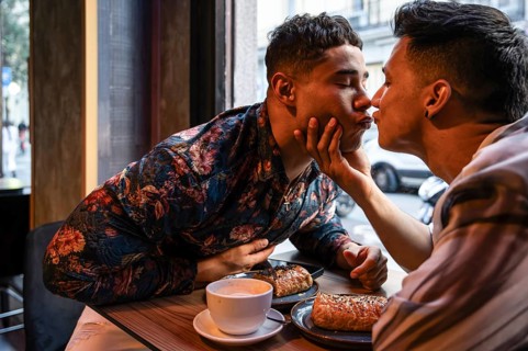 A loving latin gay couple shares a tender moment at a cafe, enjoying breakfast together. The