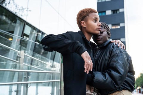 A loving LGBT multiethnic couple embraces outdoors in an urban environment. The moment captures