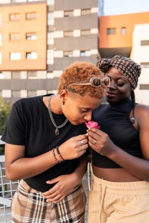 A joyful LGBT multiethnic couple shares a tender moment outdoors. One person gently sniffs a