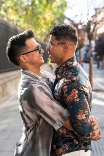 A joyful latin gay couple embraces on a sunny street in Madrid, capturing the essence of happiness