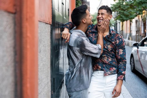 A joyful latin gay couple shares a tender moment on a vibrant street in Madrid. Their happiness and