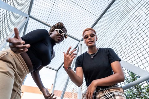 A dynamic LGBT multiethnic couple poses confidently in an urban setting. Both showcase unique