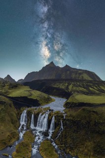 A breathtaking view of the Milky Way illuminating the night sky over a lush Icelandic landscape,