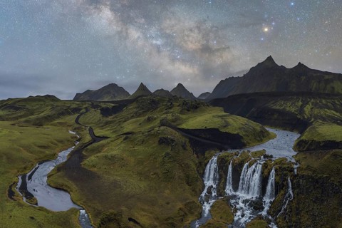 Captivating Icelandic scene with a lush green landscape, a winding river, and a cascading