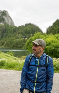 A man in outdoor gear enjoys the serene landscape at Lac de Taney, Switzerland Surrounded by lush