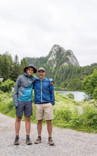 A father and son enjoy a hiking adventure at Lac de Taney, Switzerland, surrounded by lush greenery