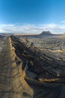 Aerial view of Caineville Mesa in Utah, showcasing rugged terrain and dramatic shadows under a vast