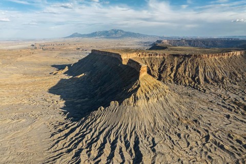 Dramatic aerial view of Caineville Mesa in Utah, USA, showcasing rugged terrain, layered rock