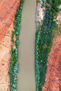 A striking aerial shot of the Rio San Juan winding through vibrant red rock landscapes, contrasted