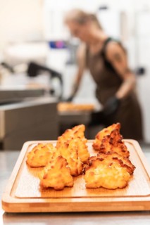 Freshly baked Italian pastries sit on a wooden board in a warm bakery A baker is seen working in