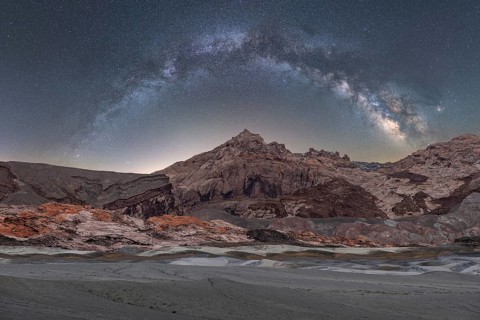A breathtaking panoramic view of the Milky Way arching over the rugged landscapes of the Utah