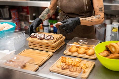 An Italian bakery scene features a person arranging freshly baked pastries on wooden trays The