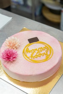 A beautifully decorated Italian cake with pink floral accents, a chocolate square, and an ornate