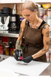 A skilled artisan in a bakery, wearing an apron and gloves, meticulously works on a piece of pastry