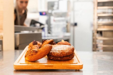 A close-up of freshly baked Italian cookies displayed on a wooden tray in a bakery setting The