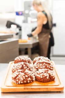 A display of freshly baked Italian pastries topped with sugar crystals on a wooden board A baker