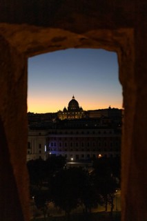 A stunning view of St Peter's Basilica framed by ancient architecture at twilight, with a vibrant