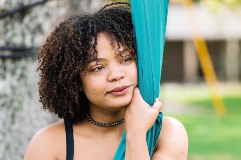 A black woman embraces silk fabric in a serene moment during a park acrobatics session in Bogota