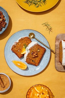 Slices of carrot cake loaf topped with rich cream cheese frosting and garnished with walnuts and