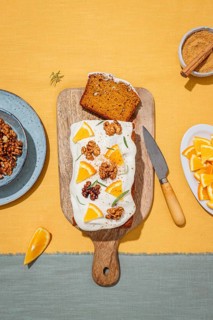 A delicious carrot cake loaf topped with creamy cream cheese frosting, garnished with orange