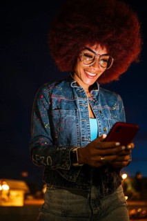 African descendent woman with a vibrant afro hairstyle, wearing glasses, joyfully engaging with her