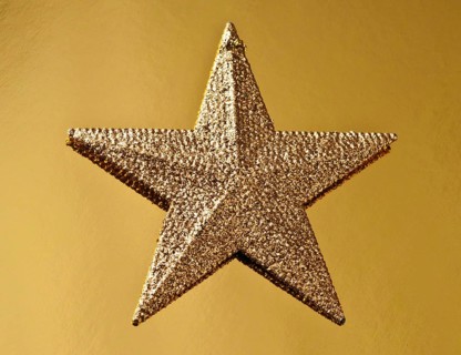 A golden Christmas star shines with a glittery surface against a textured golden background,