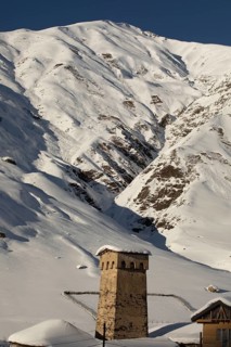 A stone tower stands amid a stunning snowy mountain landscape in Georgia The scene highlights the