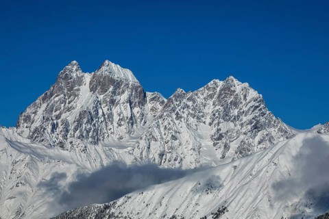 Majestic snow-covered mountain peaks tower under a clear blue sky, creating a breathtaking natural