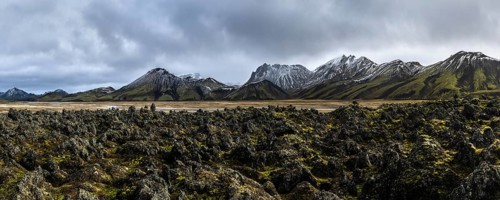 A breathtaking panoramic view of Iceland's rugged Highlands, showcasing jagged peaks, moss-covered