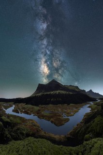 Breathtaking night sky over Iceland, capturing the Milky Way above a serene river and rugged