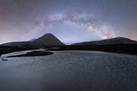 A breathtaking view of the Milky Way arching over a serene Icelandic landscape The clear, starlit
