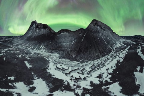 Awe-inspiring aurora borealis dances in the night sky above snow-dusted mountains and rugged