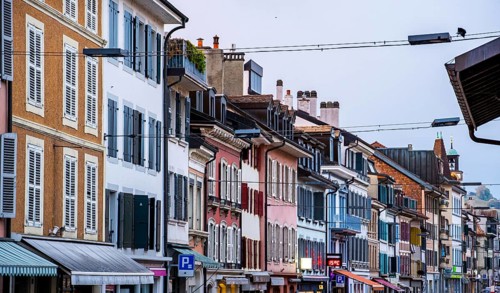 A vibrant street view of Rolle, Switzerland, showcasing colorful historic buildings with charming