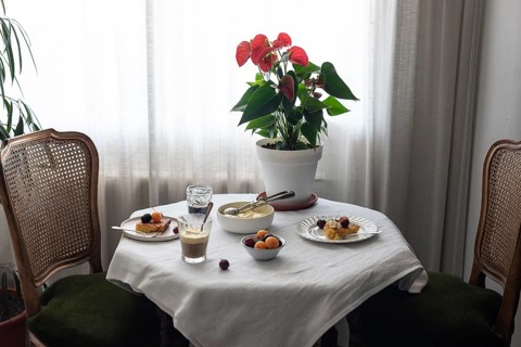 Warmly lit coffee table covered in a white cloth, featuring various desserts like cherry-topped