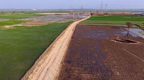 In an aerial view, people walk on a road cutting through rice paddy fields on February 16, 2026 in