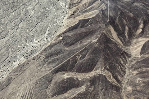Aerial photo shows hills with extensive line patterns in an arid region, the geoglyphs and images