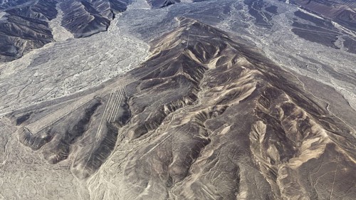 Mountain ranges in a dry desert landscape with clear geoglyph patterns, the geoglyphs and images in
