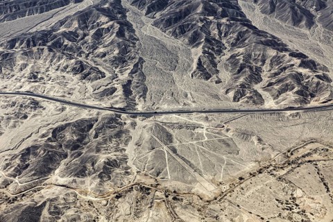 Dry, rocky desert landscape with lines and a highway, the geoglyphs and images in the desert near